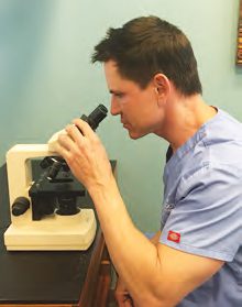 Dr. Timothy Jochen at his microscope examining a skin biopsy sample for possible skin cancer.